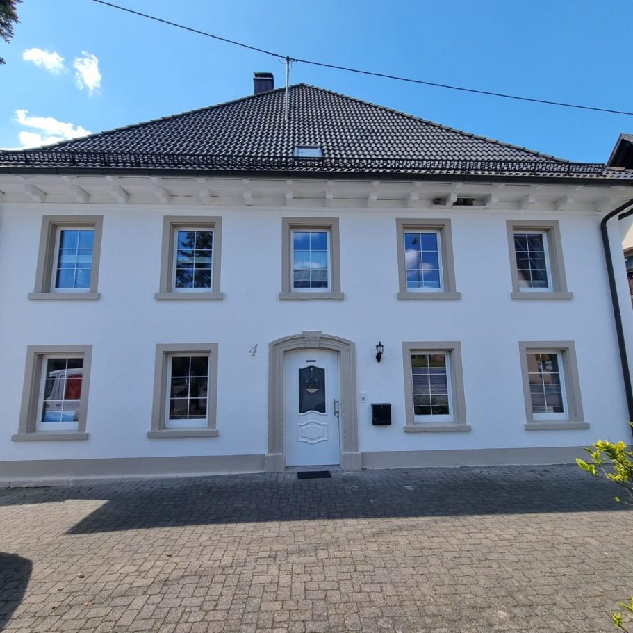 Wohnhaus mit weißer Fassade Helles, zweigeschossiges Wohnhaus mit weißer Fassade und symmetrischen Fenstern.